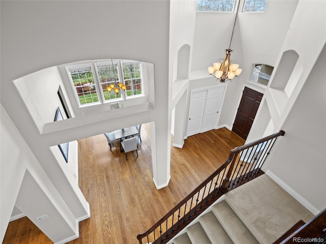 foyer with a notable chandelier, stairs, baseboards, wood finished floors, and a towering ceiling