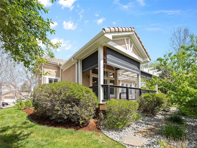 view of side of property with a deck, stucco siding, and a tiled roof