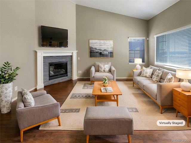 living area with lofted ceiling, a fireplace, baseboards, and wood finished floors