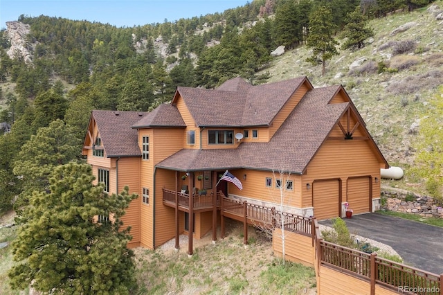 33095 Bergen Mountain Rd, Evergreen, CO 80439 - view of front of home featuring a shingled roof, a view of trees, a garage, and a deck with mountain view