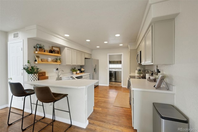 20000 Mitchell Pl Unit 9, Denver, CO 80249 - kitchen with washer / clothes dryer, stainless steel appliances, a sink, open shelves, and a kitchen breakfast bar