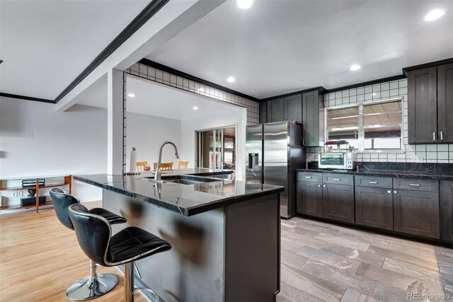 147 Wallace St, Northglenn, CO 80234 - kitchen with stainless steel refrigerator with ice dispenser, a sink, a kitchen bar, dark stone counters, and decorative backsplash