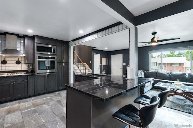 147 Wallace St, Northglenn, CO 80234 - kitchen featuring stainless steel appliances, a sink, wall chimney exhaust hood, a breakfast bar, and tasteful backsplash