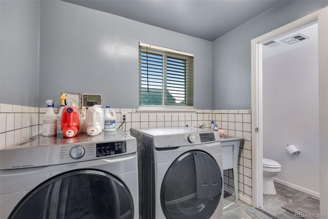 147 Wallace St, Northglenn, CO 80234 - laundry room with washer and clothes dryer and tile walls