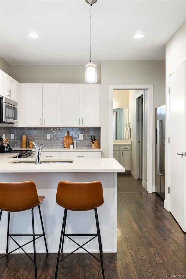 kitchen with stainless steel appliances, a breakfast bar, light countertops, and a sink