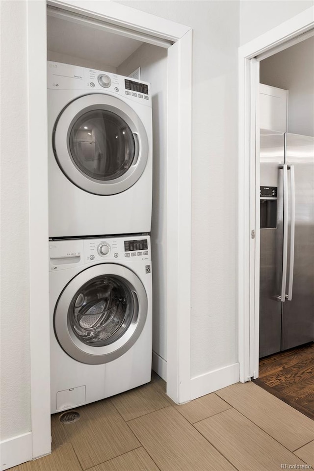 laundry room with laundry area, wood tiled floor, and stacked washer / drying machine