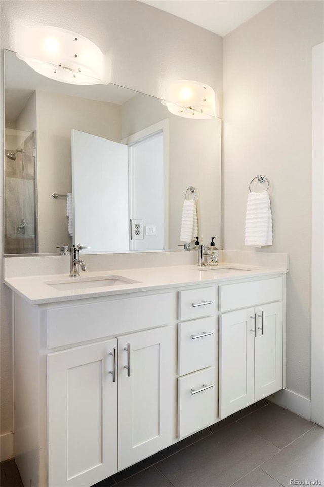 bathroom featuring double vanity, a stall shower, a sink, and tile patterned floors