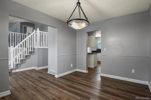 unfurnished dining area featuring a textured ceiling, dark hardwood / wood-style floors, and a notable chandelier