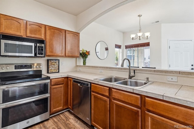 kitchen featuring hanging light fixtures, sink, dark wood-type flooring, a notable chandelier, and stainless steel appliances