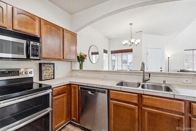 kitchen with sink, decorative light fixtures, a wealth of natural light, and stainless steel appliances