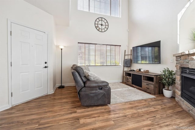 living room with a high ceiling, hardwood / wood-style floors, and a fireplace