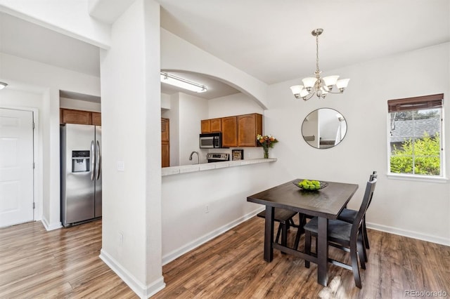 dining space with a notable chandelier, dark hardwood / wood-style floors, and sink