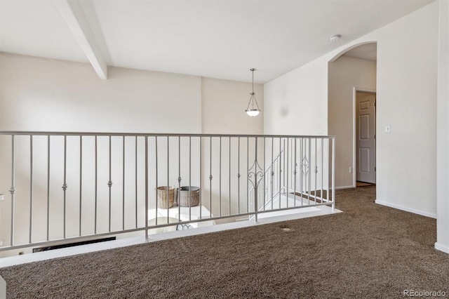 empty room featuring dark carpet and beam ceiling