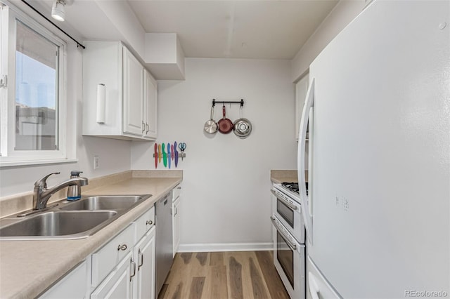 kitchen featuring white appliances, wood-type flooring, sink, and white cabinets