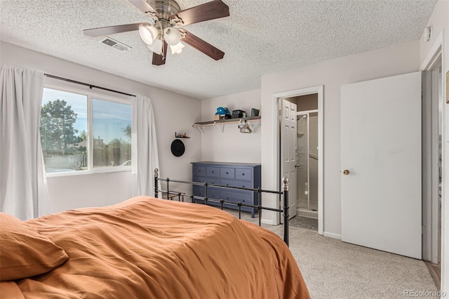 bedroom with ceiling fan, light carpet, a textured ceiling, and ensuite bathroom