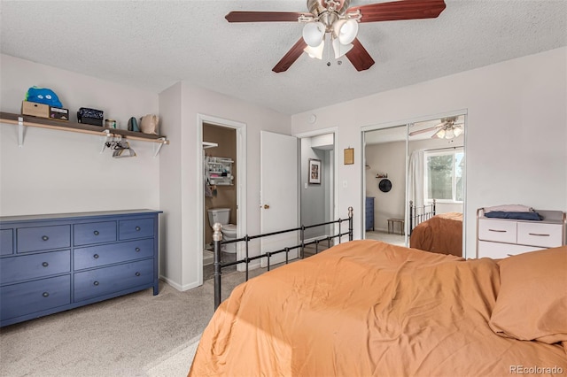 carpeted bedroom with a closet, a textured ceiling, connected bathroom, and ceiling fan