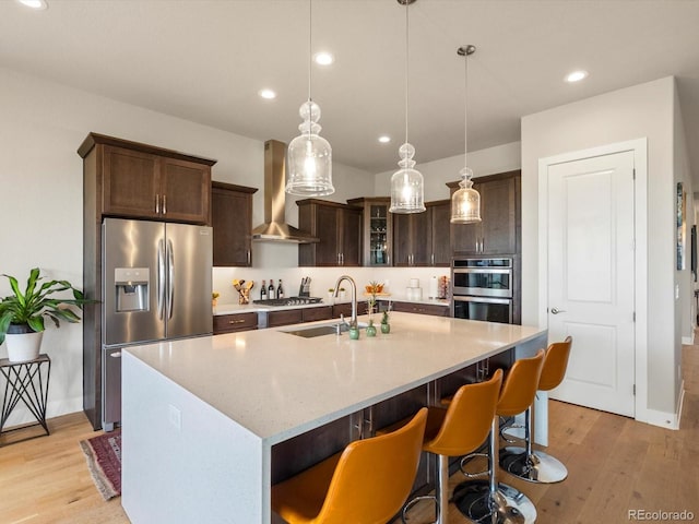 2113 Fountain Cir, Erie, CO 80516 - kitchen featuring appliances with stainless steel finishes, a sink, wall chimney range hood, light wood finished floors, and recessed lighting