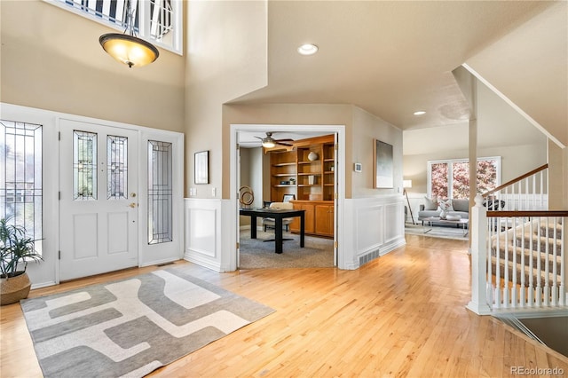 entrance foyer with hardwood / wood-style floors, ceiling fan, and a towering ceiling