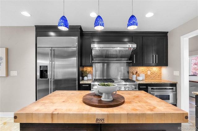 kitchen featuring tasteful backsplash, pendant lighting, wall chimney range hood, and appliances with stainless steel finishes