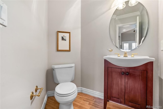 bathroom with hardwood / wood-style floors, vanity, toilet, and ornamental molding