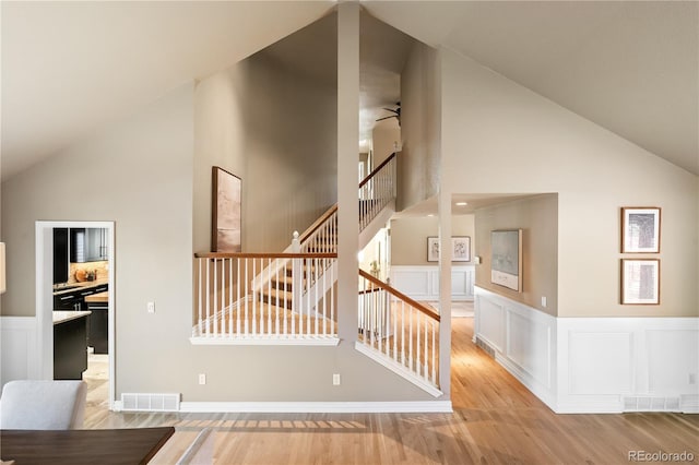 stairway featuring hardwood / wood-style flooring, ceiling fan, and high vaulted ceiling