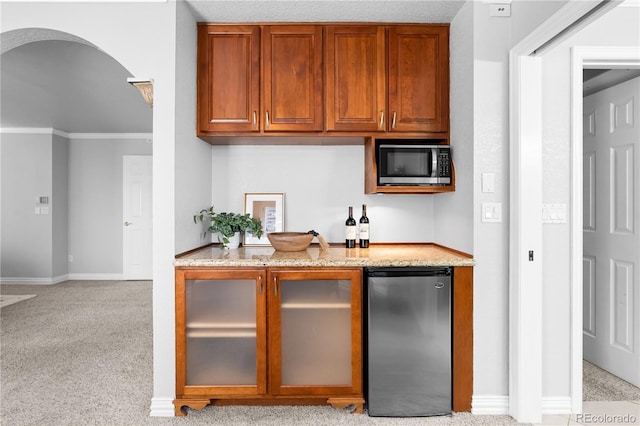 kitchen featuring light stone countertops, crown molding, light colored carpet, and stainless steel appliances