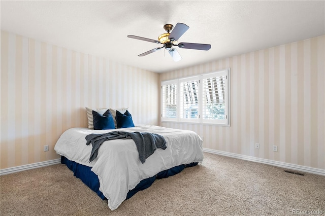 carpeted bedroom featuring ceiling fan and a textured ceiling