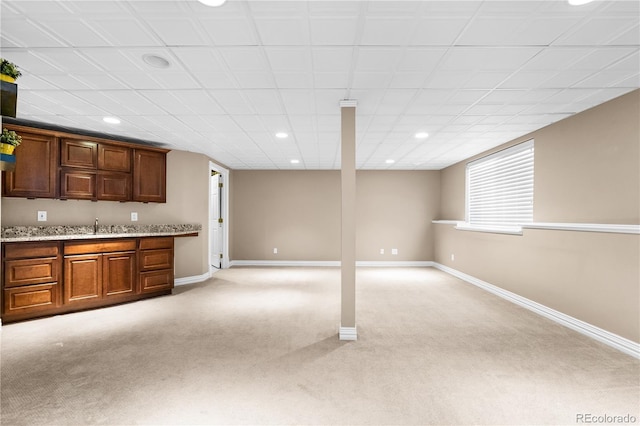 kitchen featuring light stone counters, sink, and light colored carpet