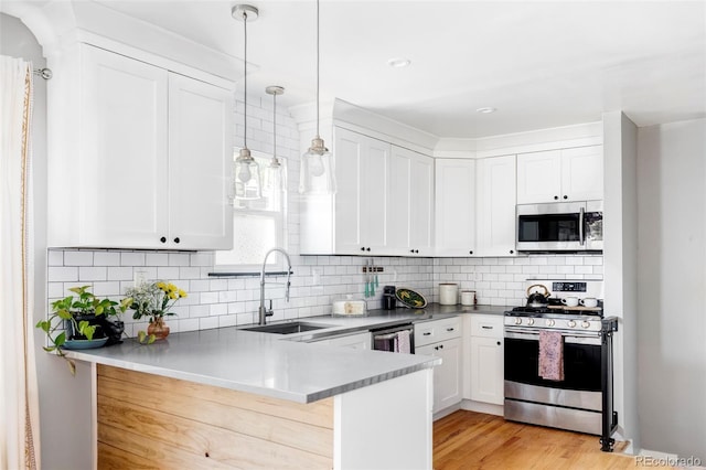 3509 N Monroe St, Denver, CO 80205 - kitchen featuring appliances with stainless steel finishes, a peninsula, white cabinets, tasteful backsplash, and pendant lighting