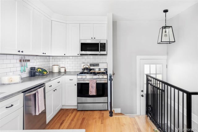 3509 N Monroe St, Denver, CO 80205 - kitchen with appliances with stainless steel finishes, backsplash, white cabinets, and light wood finished floors
