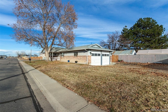 exterior space with a yard, brick siding, an attached garage, and fence