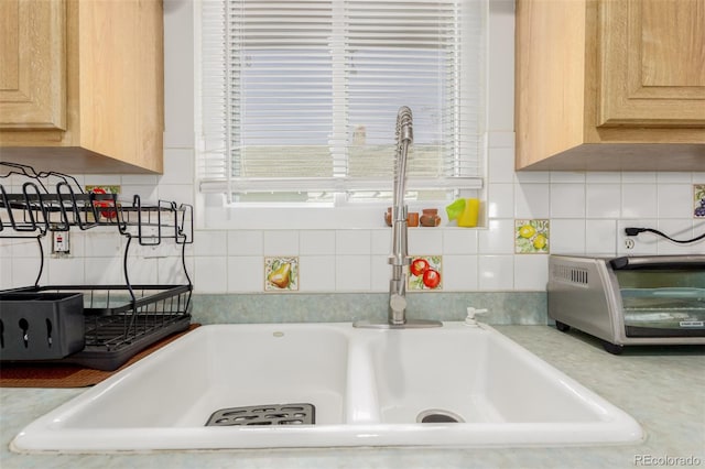 room details featuring a toaster, light brown cabinets, light countertops, and backsplash