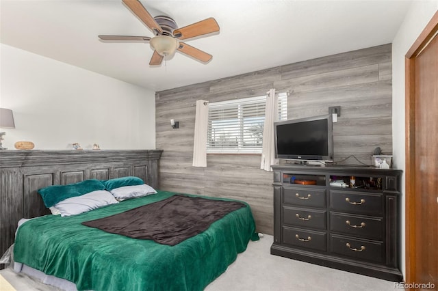 carpeted bedroom featuring wood walls and ceiling fan