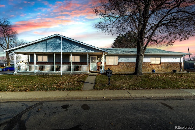 view of front of property featuring covered porch, a carport, and brick siding