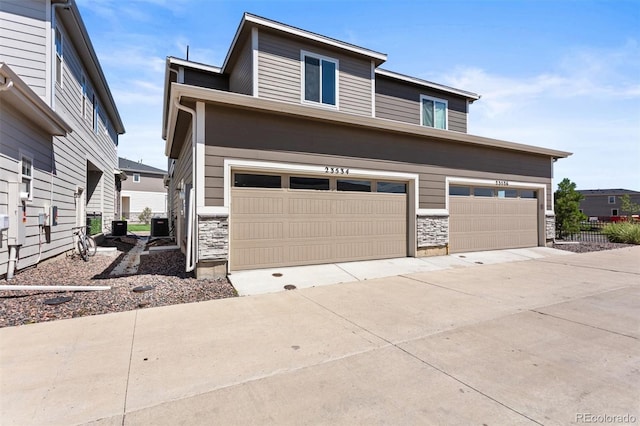 23534 E 5th Pl, Aurora, CO 80018 - view of front of house featuring stone siding, a garage, and driveway