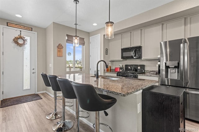 23534 E 5th Pl, Aurora, CO 80018 - kitchen with black microwave, stove, stainless steel fridge with ice dispenser, light wood-style floors, and light stone counters