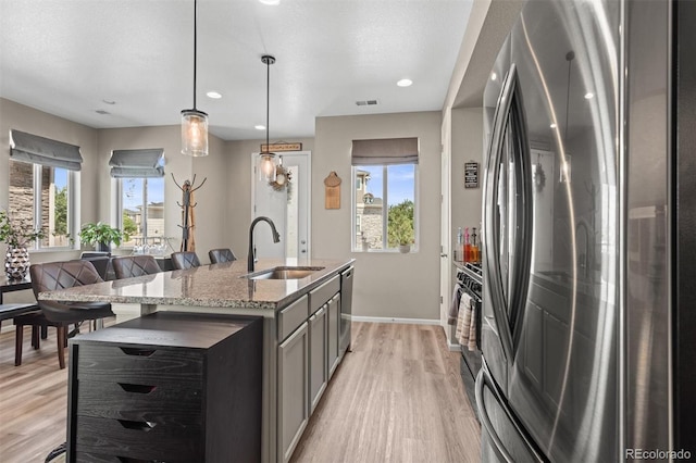 23534 E 5th Pl, Aurora, CO 80018 - kitchen featuring stainless steel appliances, light wood-style floors, light stone countertops, hanging light fixtures, and gray cabinetry