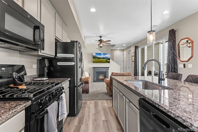 23534 E 5th Pl, Aurora, CO 80018 - kitchen featuring black appliances, a ceiling fan, light wood finished floors, a glass covered fireplace, and open floor plan