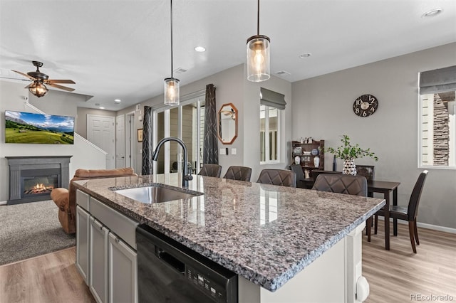 23534 E 5th Pl, Aurora, CO 80018 - kitchen featuring dishwasher, open floor plan, light wood-style floors, a glass covered fireplace, and an island with sink