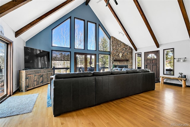 1567 Tapadero Rd, Bailey, CO 80421 - living room with high vaulted ceiling, beam ceiling, a stone fireplace, light wood-style flooring, and plenty of natural light