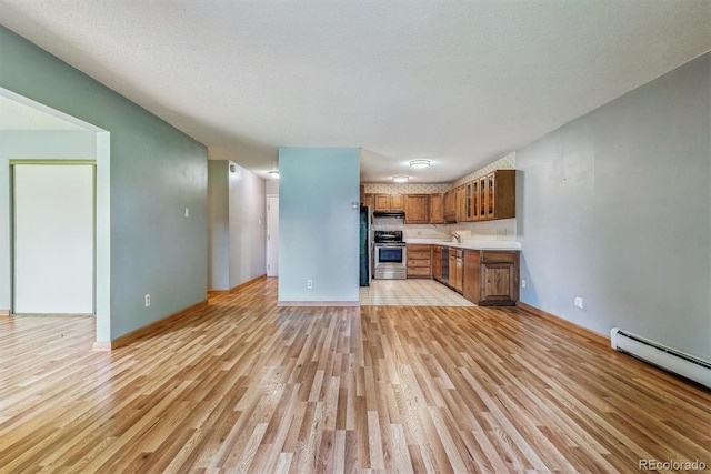 unfurnished living room featuring light wood-style floors, a baseboard radiator, baseboards, and a sink