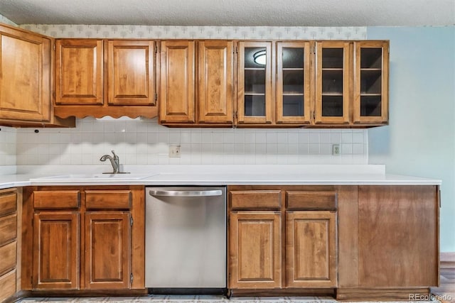 kitchen with stainless steel dishwasher, a sink, brown cabinets, decorative backsplash, and light countertops