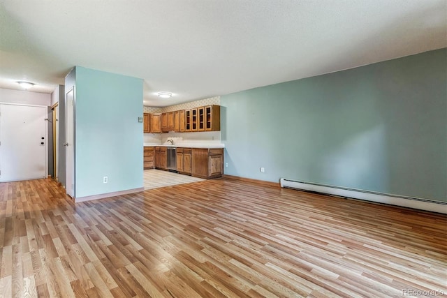 unfurnished living room featuring light wood-style flooring, baseboard heating, and baseboards