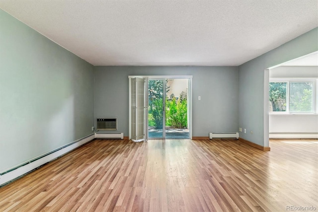 unfurnished living room with baseboard heating, healthy amount of natural light, wood finished floors, baseboards, and a textured ceiling