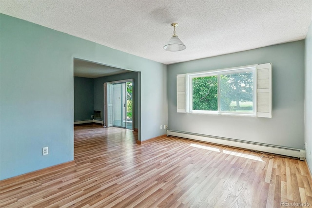 unfurnished room featuring a baseboard heating unit, healthy amount of natural light, wood finished floors, and a textured ceiling