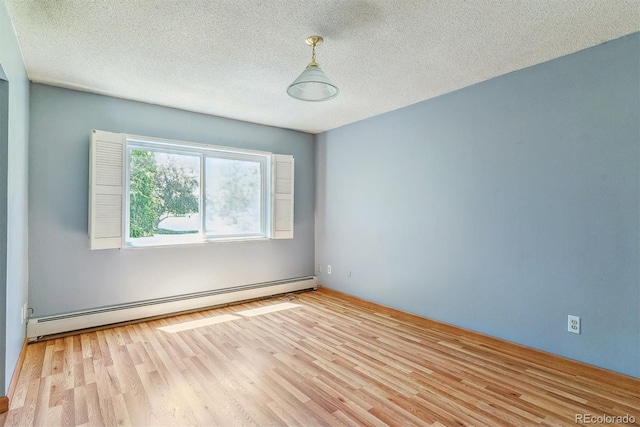 spare room with baseboard heating, wood finished floors, and a textured ceiling