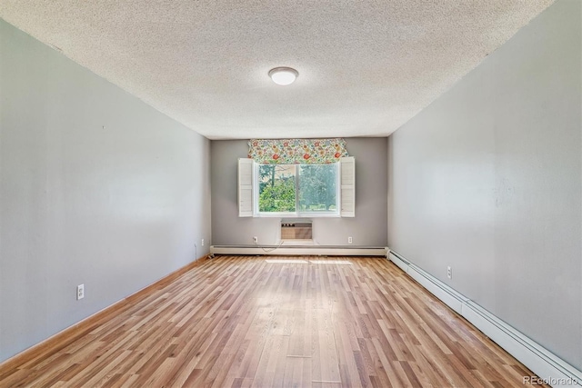 spare room with a baseboard radiator, a baseboard heating unit, light wood finished floors, a textured ceiling, and an AC wall unit
