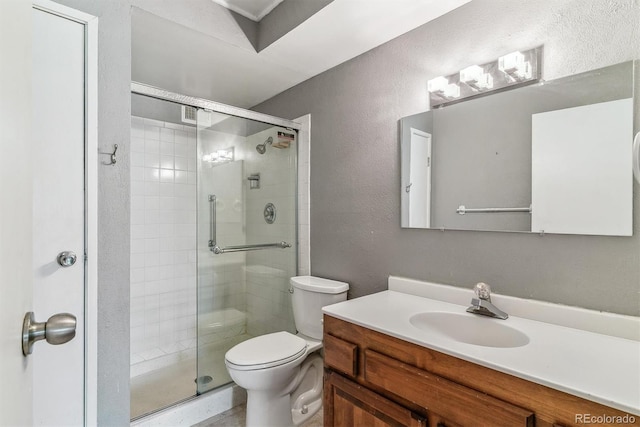 bathroom with toilet, a stall shower, a textured wall, and vanity