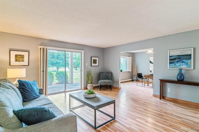 13626 E Bates Ave Unit 110, Aurora, CO 80014 - living room with healthy amount of natural light, light wood-style flooring, a textured ceiling, and baseboard heating