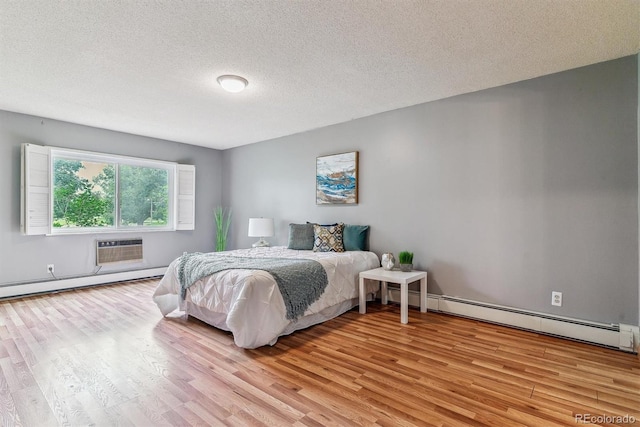 13626 E Bates Ave Unit 110, Aurora, CO 80014 - bedroom with baseboard heating, light wood-style floors, a wall unit AC, and a textured ceiling